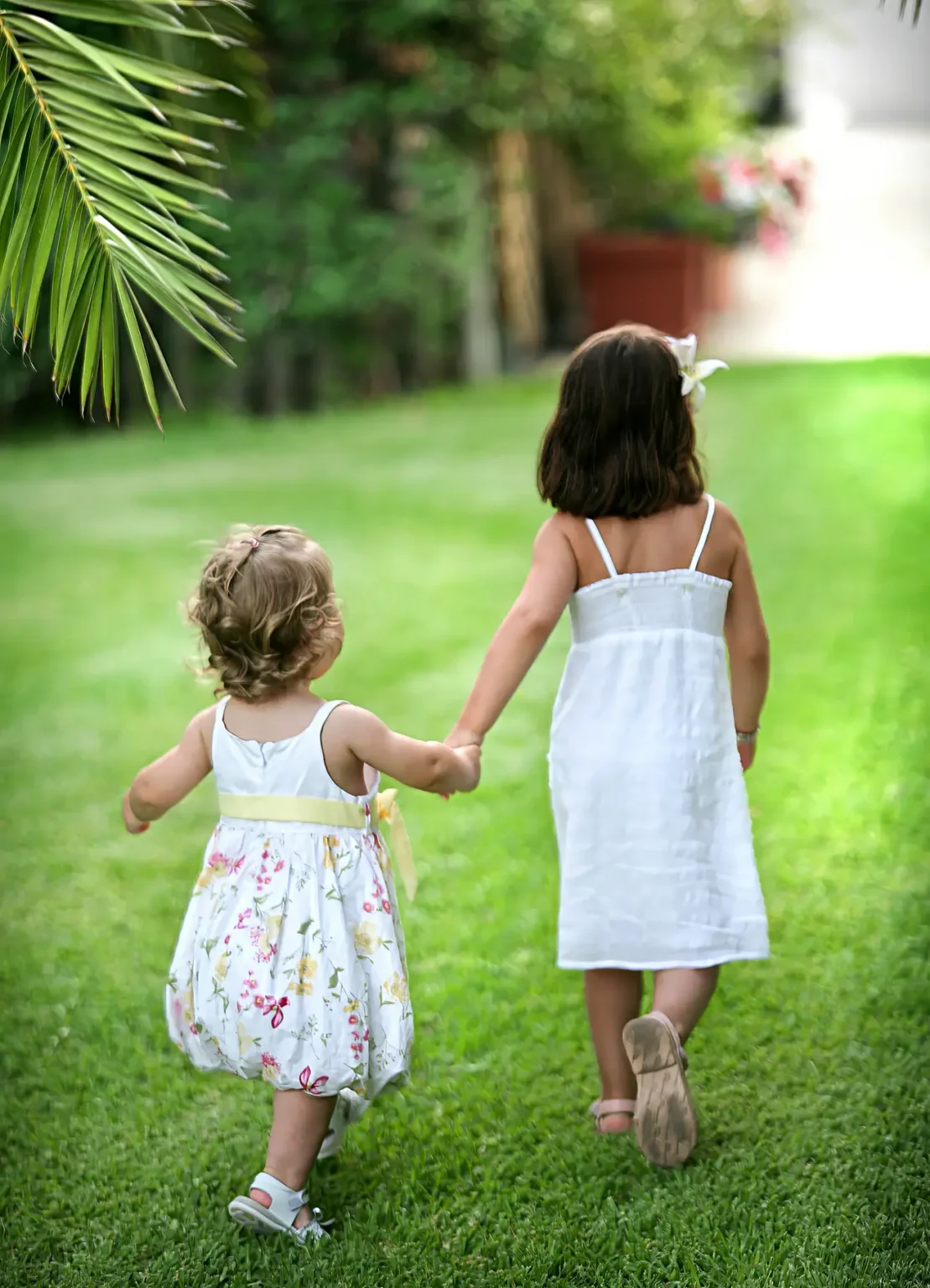 two girls holding hands walking on grass