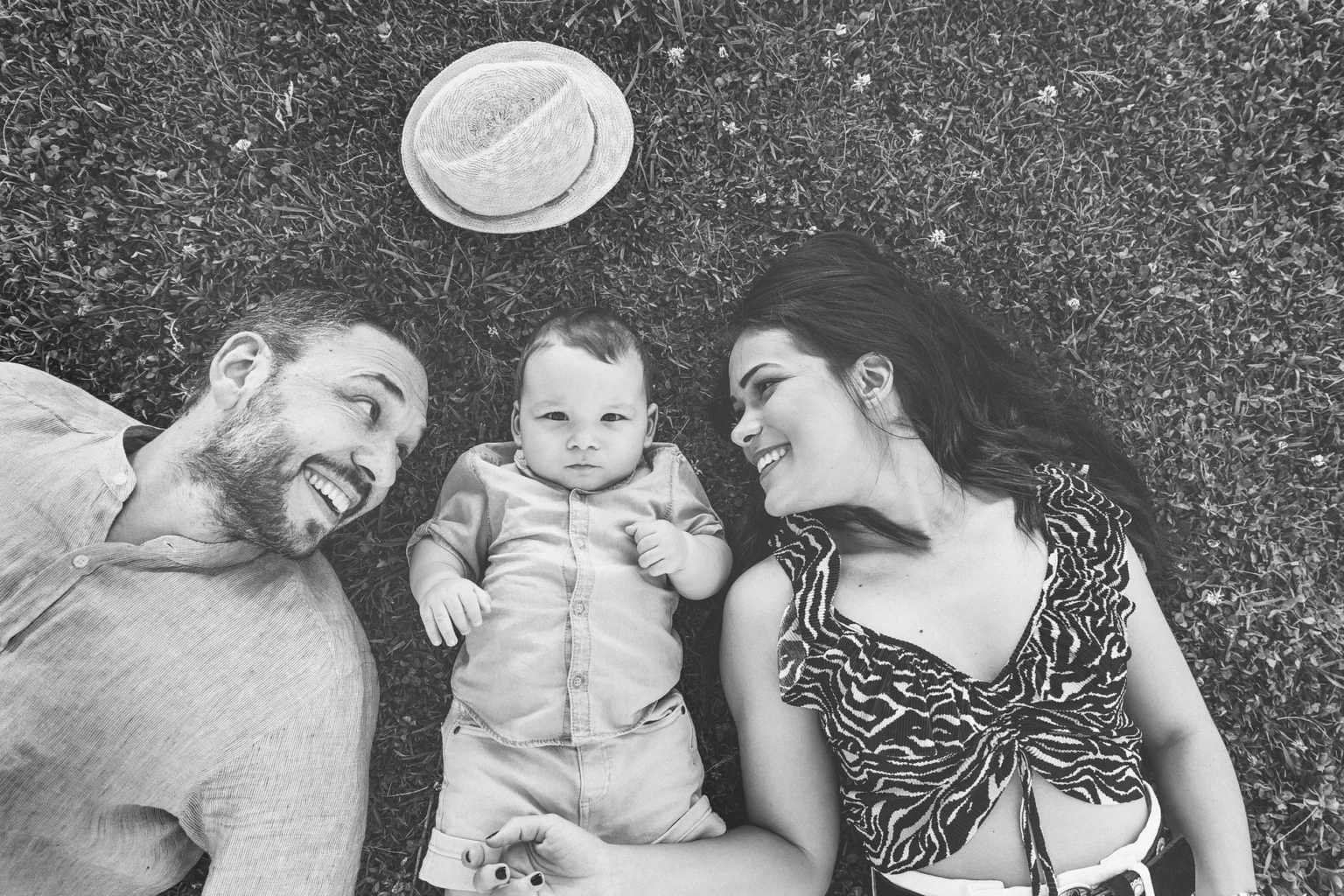 a man and woman lying on grass with a baby