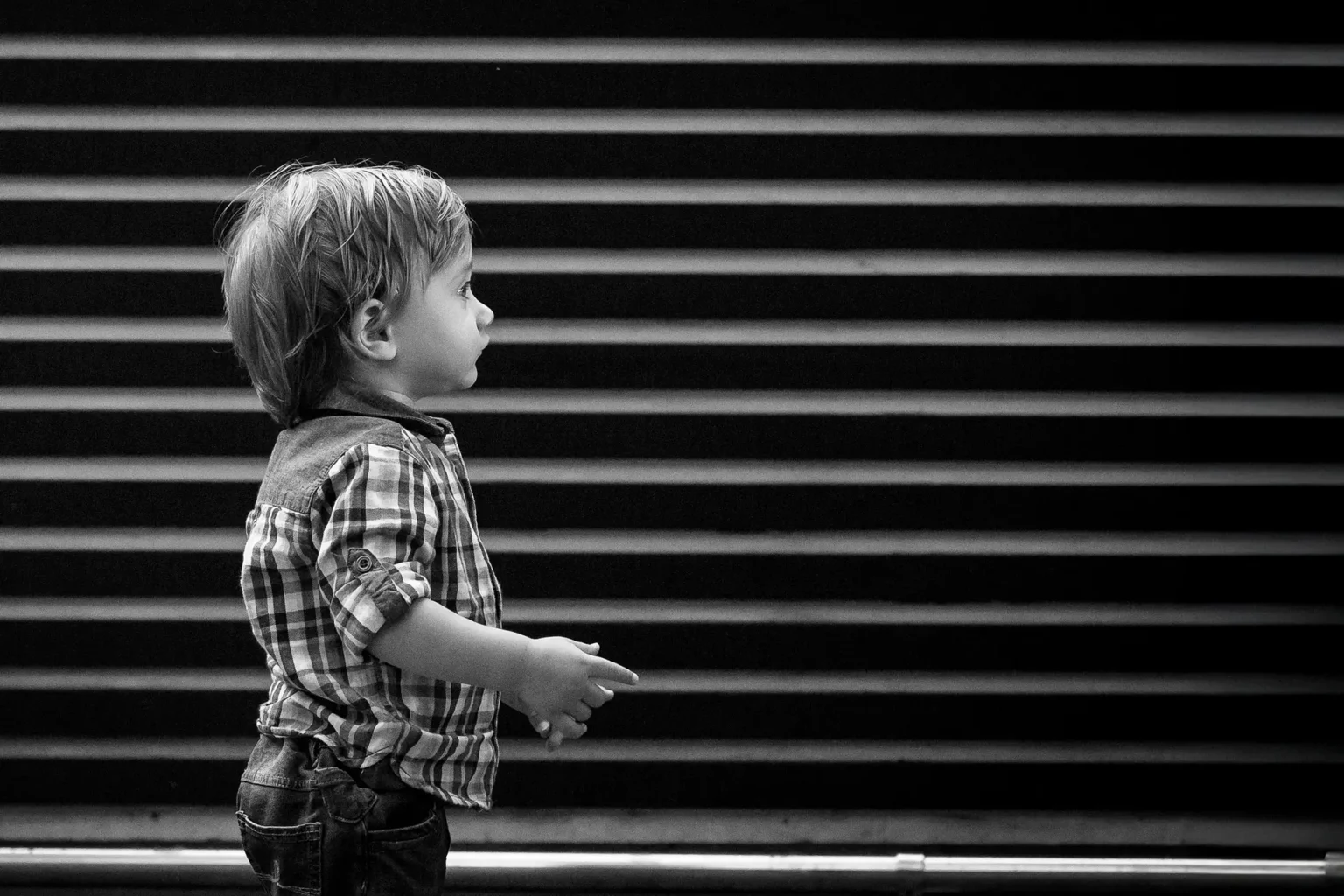 a child standing in front of a blinds