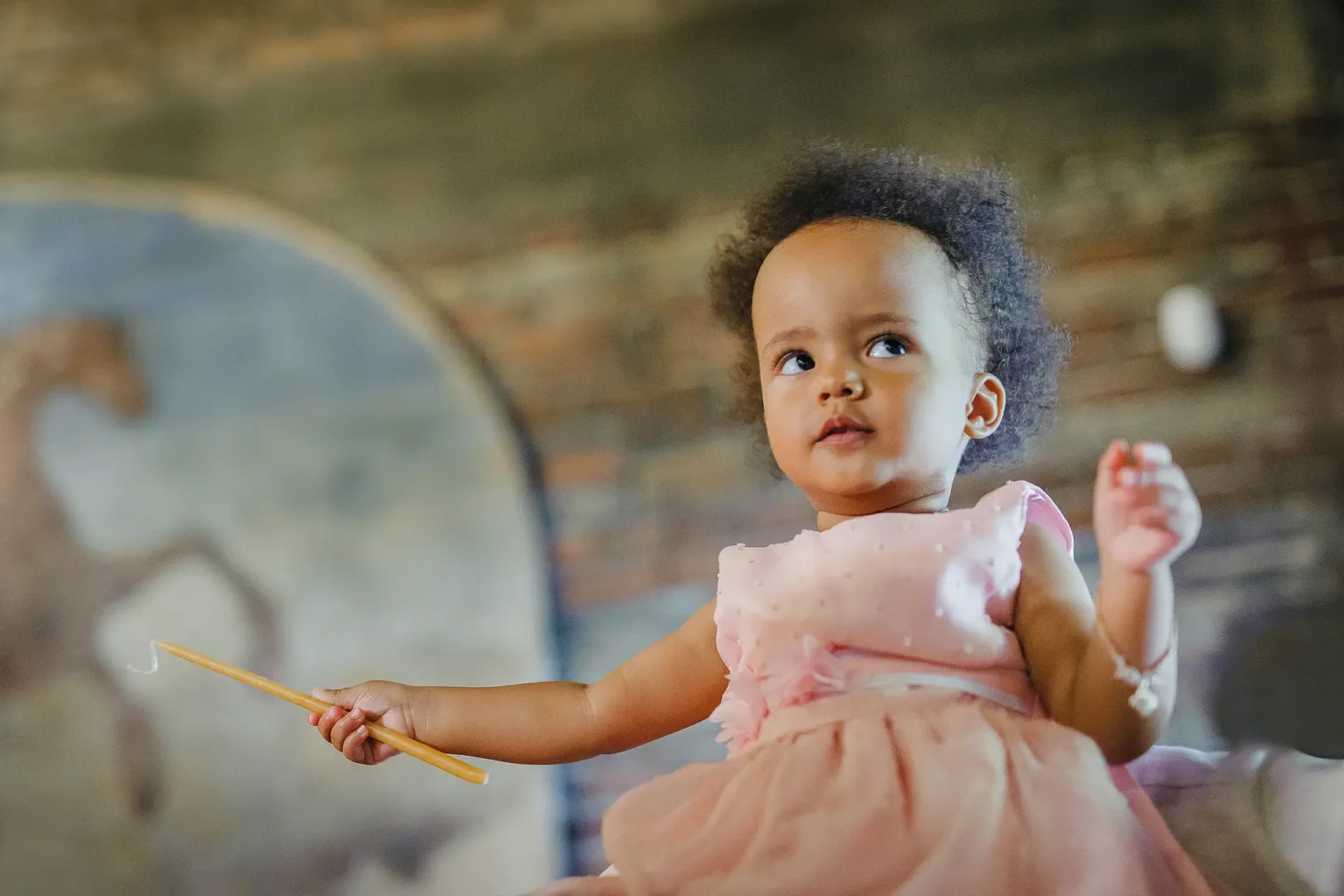 a baby girl in a pink dress holding a wand