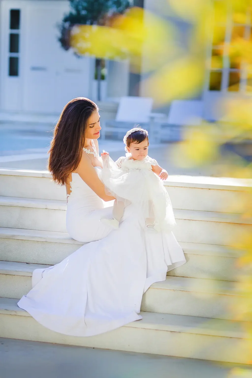 a woman in a white dress holding a baby