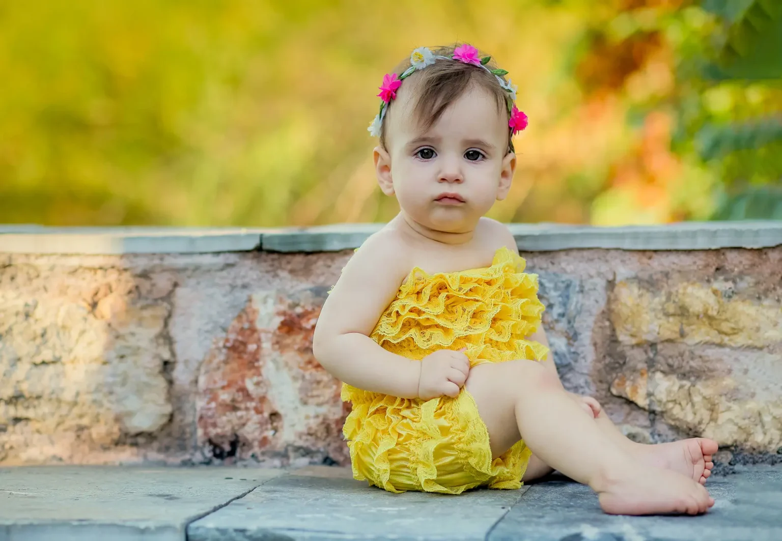 a baby sitting on a stone wall