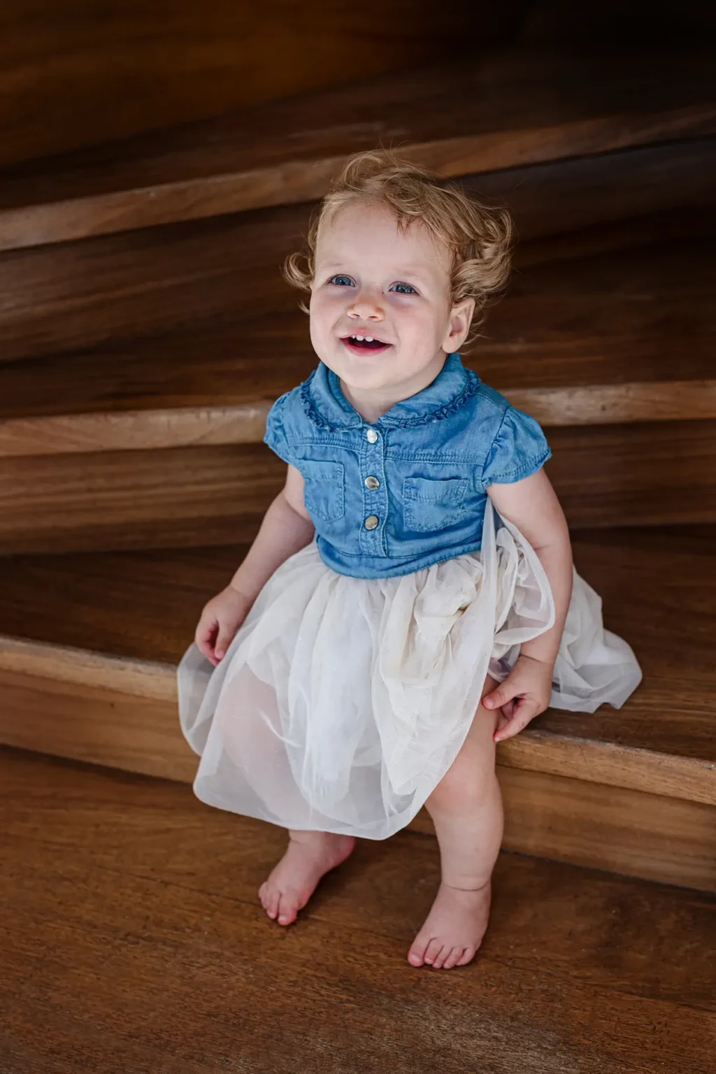 a baby sitting on a wooden staircase