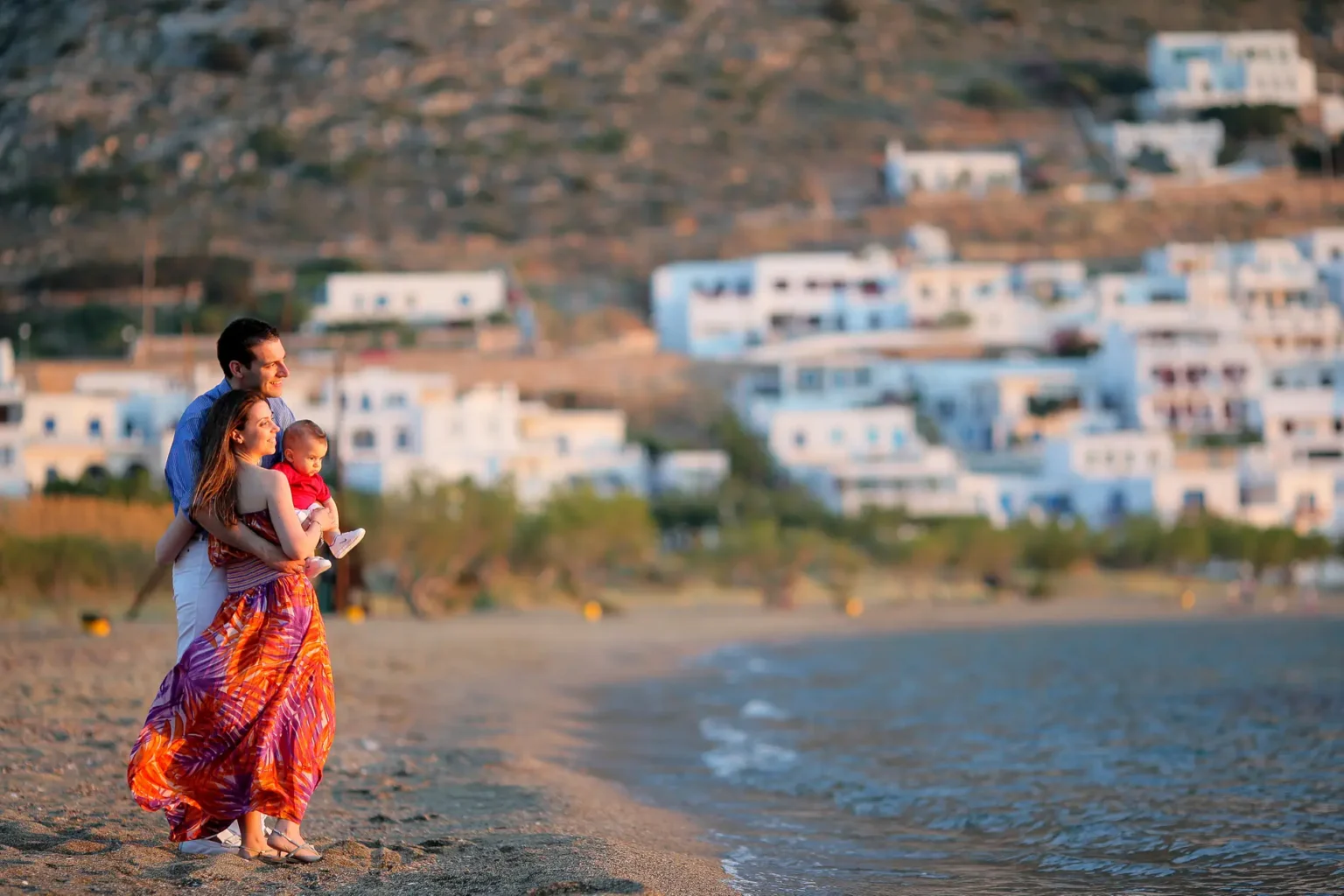 a man and woman holding a baby on a beach