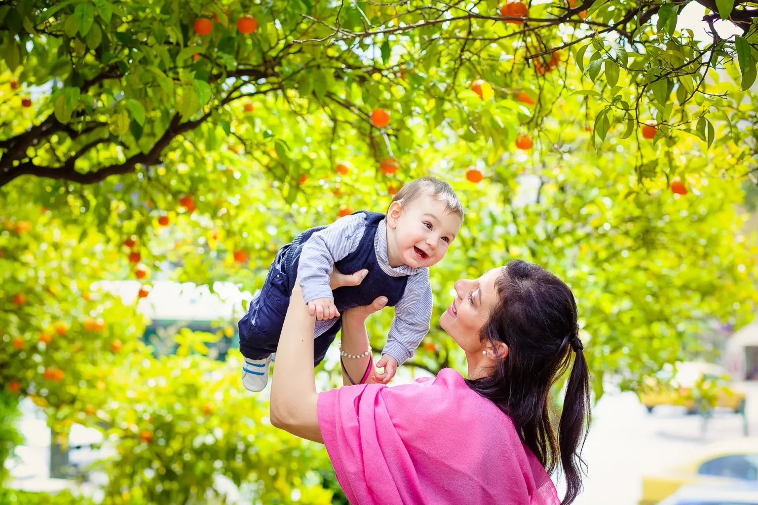 a woman holding a baby under a tree