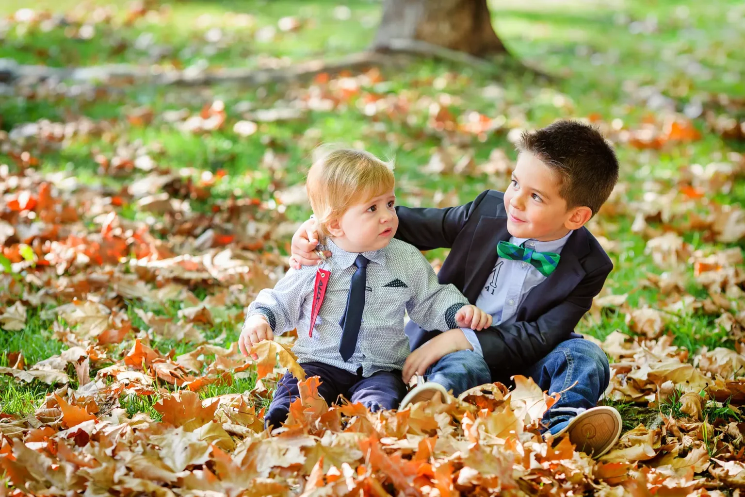 a boy sitting in the leaves