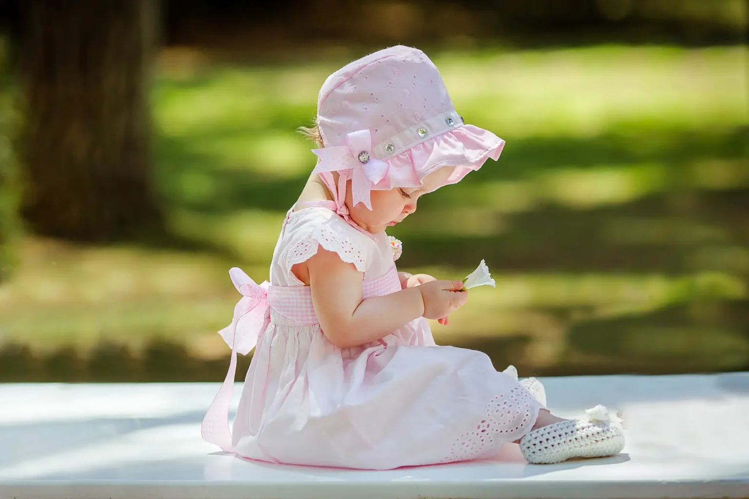 a baby girl in a pink dress and hat