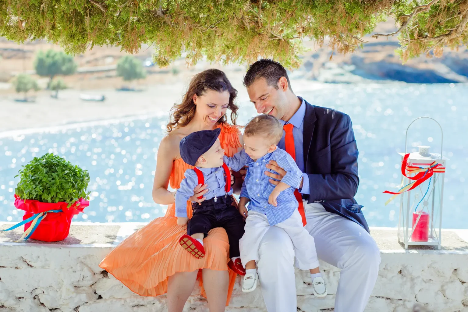 a man and woman sitting on a ledge with two children