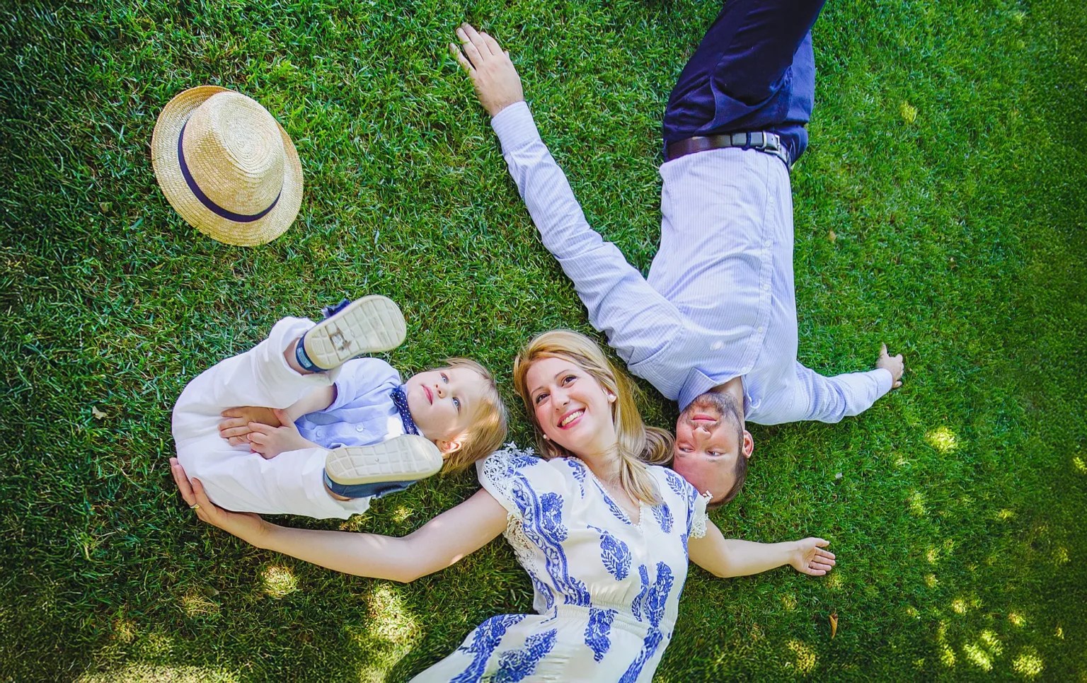 a man and woman lying on grass with a baby