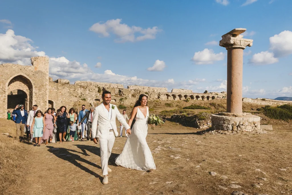a man and woman in white wedding attire walking down a dirt path