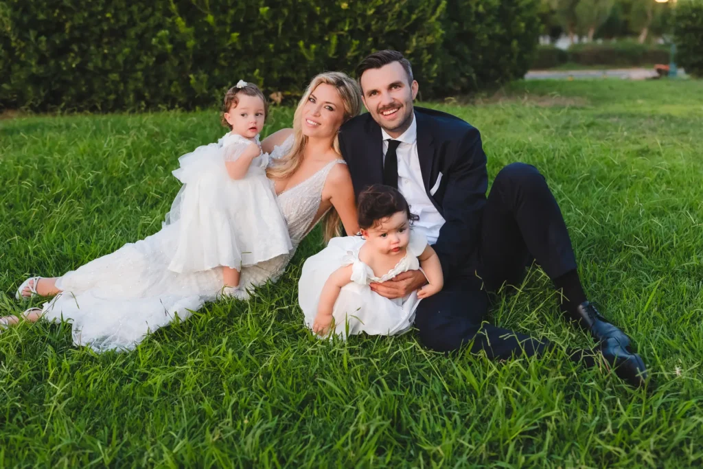 a man and woman in white dresses and a couple of children in grass