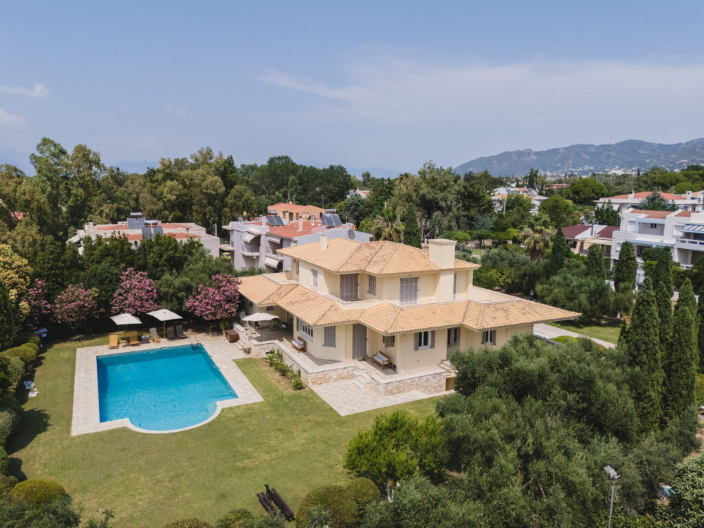 Διώροφη κίτρινη βίλα με πισίνα, καταπράσινο κήπο και δέντρα